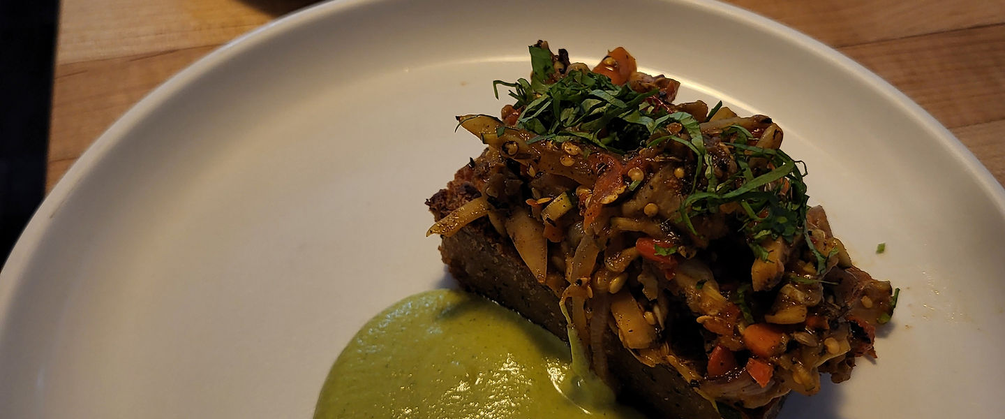 Plated private dinner course with herbs and green sauce